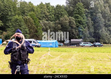 Soldaten der polnischen Armee umkreisen eine Gruppe von Einwanderern aus Afghanistan an der weißrussischen Grenze und verhindern ihre Einreise in das Land in Usnarz Gorny, Polen, am 27. August 2021. Die Armee und die Polizei hielten die Migranten an der Grenze an und verhinderten, dass sie nach Polen einmarschieren konnten, die Armee verweigerte auch den Zugang zu Asylverfahren, medizinischer Hilfe und Lebensmitteln. Journalisten und Wohltätigkeitsarbeiter werden etwa 300 Meter entfernt gehalten. Die Aktionen der polnischen Regierung wurden weithin kritisiert. Die polnische Regierung beschloss außerdem, einen Zaun zu errichten, um dem Zustrom von Migranten, die über Belarus wandern, ein Ende zu setzen b Stockfoto