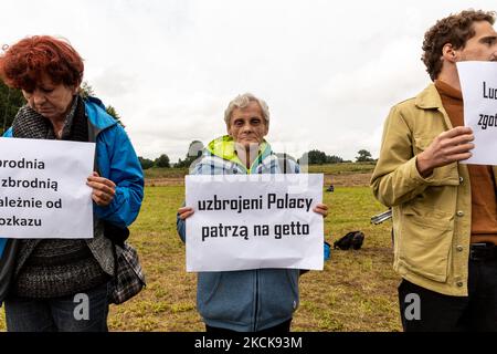 Aktivisten protestieren, während Soldaten der polnischen Armee eine Gruppe von Einwanderern aus Afghanistan an der weißrussischen Grenze umkreisen und ihre Einreise in das Land in Usnarz Gorny, Polen, am 27. August 2021 verhindern. Die Armee und die Polizei hielten die Migranten an der Grenze an und verhinderten, dass sie nach Polen einmarschieren konnten, die Armee verweigerte auch den Zugang zu Asylverfahren, medizinischer Hilfe und Lebensmitteln. Journalisten und Wohltätigkeitsarbeiter werden etwa 300 Meter entfernt gehalten. Die Aktionen der polnischen Regierung wurden weithin kritisiert. Die polnische Regierung beschloss auch, einen Zaun zu bauen, um dem Zustrom von Wanderern ein Ende zu setzen Stockfoto