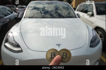 Illustrative Abbildung von zwei Gedenkbitcoins, die vor dem Tesla Model X Auto zu sehen sind. Donnerstag, 26. August 2021, in Edmonton, Alberta, Kanada. (Foto von Artur Widak/NurPhoto) Stockfoto