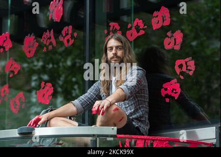 LONDON, VEREINIGTES KÖNIGREICH - 27. AUGUST 2021: Umweltaktivisten vom Extinction Rebellion sitzen auf dem Eingang des Standard Chartered, der während eines Protestes gegen die Unternehmen und Institutionen, die finanzieren, rote Farbe über die Fenster verschüttet hat. Die Sicherung und Ermöglichung großer fossiler Energieprojekte und die Gewinnung von Ressourcen in den Entwicklungsländern des Globalen Südens, die Änderung des Kolonialsystems fordern, das die Klima- und Rassismus-Krisen am 27. August 2021 in London, England, antreibt. Extinction Rebellion-Aktivisten zielen während der zwei Wochen „Impossi“ auf die City of London Stockfoto