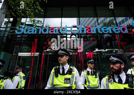 Klimaaktivisten von Extinction Rebellion stellen sich während ihres "Blutgeldmarsches"-Protests im Rahmen ihrer Kampagne „Impossible Rebellion“ in London, Großbritannien, am 27. August 2021 vor die Büros von Standard Chartered Plc. Die Klimaschutzgruppe Extinction Rebellion (XR) plant, ab August 23. 2021 mehrere Aktionen in zwei Wochen durchzuführen, um die City of London und darüber hinaus zu stören und den Klimawandel vor dem Gipfel COP26 im Vereinigten Königreich im Laufe dieses Jahres ganz oben auf die Tagesordnung zu setzen. (Foto von Maciek Musialek/NurPhoto) Stockfoto