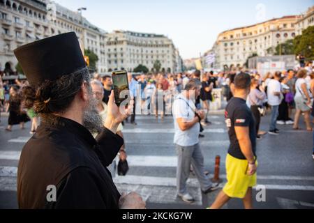 Ein Priester streamt den Protest live. Hunderte von Demonstranten mit Transparenten, wie sie auf dem Aristoteles-Platz zu sehen waren. In der Stadt Thessaloniki fanden mehrere Proteste mit Tausenden von Demonstranten statt. Die Demonstration war gegen die verpflichtende COVID-19-Impfmaßnahme der Beschäftigten im öffentlichen Gesundheitswesen, Ärzte und Lehrer zur Bekämpfung der Pandemie ab dem 1. September werden 2021 nicht geimpfte Regierungsmitarbeiter im Gesundheitssektor ausgesetzt. Tausende von Demonstranten kamen aus Nordgriechenland, das stundenlang im Stadtzentrum marschierte, nachdem sie Reden gehalten hatten. Unter den Demonstranten Christian Ort Stockfoto