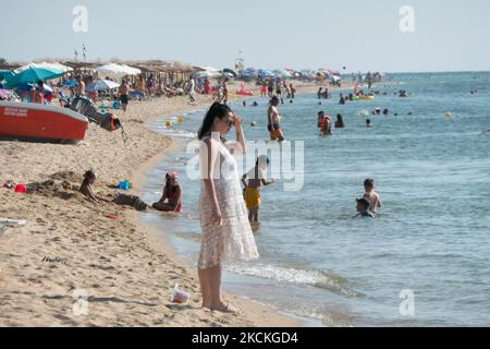 Tägliches Leben am Strand mit Touristen, hauptsächlich vom Balkan und Einheimischen, die die Sonne, das Meer, den Strand von Nea Iraklia oder Paralia Irakleia in Chalkidiki genießen. Der Sandstrand mit dem kristallklaren Meerwasser hat viele Strandbars, die Sonnenschirme und Sonnenliegen, Schatten und kalte Getränke anbieten, während Strandbesucher schwimmen, sonnenbaden, entspannen und das Meer genießen können. Die Menschen genießen das Wasser am Ufer, als eines der letzten Wochenenden der Sommersaison. Griechenland ist stark auf den Tourismussektor angewiesen, eine Branche, auf die die Coronavirus-Pandemie Covid-19 dramatische Auswirkungen hatte. Die Bea Stockfoto