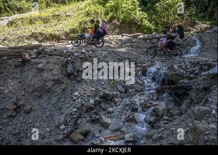 Autofahrer überqueren die Trans Palu-Kulawi Road, die am 31. August 2021 in Namo Village, Sigi Regency, Central Sulawesi Province, Indonesien, von Erdrutschmaterial bestattet wird. Die Straße, die Palu City und Sigi Regency verbindet, wurde seit August 28 an fünf Punkten durch Erdrutschmaterial durch starken Regen mit hoher Intensität vergraben und bisher können nur zweirädrige Fahrzeuge fahren. (Foto von Basri Marzuki/NurPhoto) Stockfoto