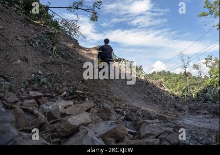 Ein Autofahrer geht am 31. August 2021 auf der Trans Palu-Kulawi Road, die von Erdrutschmaterial in Namo Village, Sigi Regency, Central Sulawesi Province, Indonesien, begraben ist. Die Straße, die Palu City und Sigi Regency verbindet, wurde seit August 28 an fünf Punkten durch Erdrutschmaterial durch starken Regen mit hoher Intensität vergraben und bisher können nur zweirädrige Fahrzeuge fahren. (Foto von Basri Marzuki/NurPhoto) Stockfoto