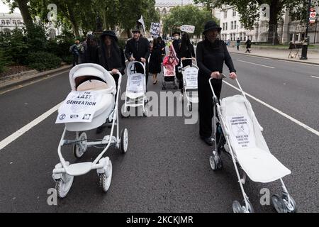 LONDON, GROSSBRITANNIEN – 31. AUGUST 2021: Aktivisten des Extinction Rebellion in schwarzer Kleidung inszenieren am 31. August 2021 in London, England, einen trauermarsch mit weiß gestrichenen Kinderwagen vom Parliament Square zum Trafalgar Square, in dem die britische Regierung angesichts der Klimakrise und der ökologischen Notlage einen sofortigen Stopp aller Investitionen in fossile Brennstoffe forderte. Die Aktion ist Teil der „Unmöglichen Rebellion“, einer neuen Welle von Protesten und zivilen Ungehorsamsmaßnahmen, die sich an Regierungen und Finanzinstitutionen richten. (Foto von Wiktor Szymanowicz/NurPhoto) Stockfoto