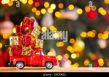 Roter Retro-Spielzeugtruck trägt Geschenke auf dem Hintergrund des Weihnachtsbaums Stockfoto