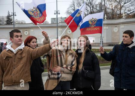 Moskau, Russland. 4.. November, 2022 Menschen winken russische Fahnen während eines Flashmob "Wir sind vereint" am Haupteingang des VDNKh Ausstellungszentrums und Park am Tag der Nationalen Einheit Russlands, in Moskau, Russland Stockfoto