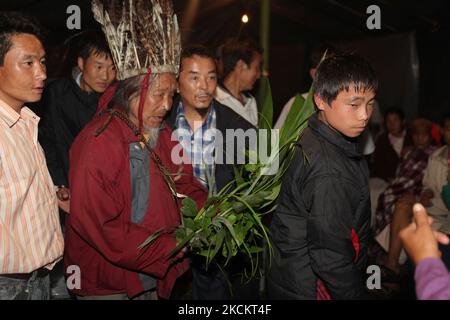 Ein 90-jähriger Lepcha-Bomthing (Lepcha-Priester), der einen gefiederten Hut trägt, singt Gebete und segnet einen Dorfjungen mit Blättern während einer Tieropferzeremonie, um böse Geister in einem kleinen Dorf tief im Dschungel in Sikkim, Indien, am 05. Juni 2010 zu besänftigen. Viele Dorfbewohner sind ohne jegliche Unterstützung gestorben, deshalb haben die Dörfer von Lepcha die Bombe geschickt, um die bösen Geister zu beseitigen, die im Dorf zu Tode kamen. Diese Zeremonie soll das Dorf 180 Jahre lang schützen, nachdem es vorgeformt wurde. (Foto von Creative Touch Imaging Ltd./NurPhoto) Stockfoto