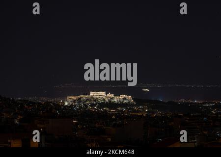 Nachtansicht des Parthenon und der Akropolis mit einer Fähre, die im Hintergrund in der griechischen Hauptstadt Athina vorbeifährt. Langzeitbelichtung Fotografie Technik zeigt die Antiquitäten im Dunkeln beleuchtet mit der städtischen Landschaft der Stadt um.. Der alte Hügel der Akropolis, einschließlich des weltweit bekannten marmorierten Tempels Parthenon und der Überreste vieler antiker Gebäude von großer architektonischer und historischer Bedeutung wie dem Erechtheion, Propylaia, dem Tempel der Athene Nike, den Karyaden und mehr. Während der osmanischen Besatzung wurde die Akropolis schwer beschädigt. Es ist heute UNESCO-Welterbe Stockfoto