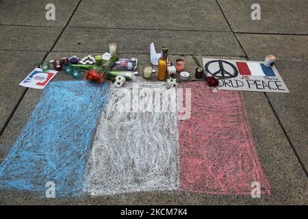 14. November 2015, Toronto, Ontario, Kanada --- Kanadier setzen Kerzen und Blumen an einer französischen Flagge während einer Mahnwache auf dem Nathan Phillips Platz in Toronto, Kanada, um einen Tag nach den Terroranschlägen in Paris Solidarität mit den Bürgern Frankreichs zu zeigen. Dschihadisten des Islamischen Staats behaupteten am 13. November in Paris eine Reihe koordinierter Angriffe von Schützen und Selbstmordattentätern, bei denen mindestens 129 Menschen getötet und mehr als 350 bei Szenen des Gemetzels in einer Konzerthalle, Restaurants und im Nationalstadion verletzt wurden. Dieser Angriff ist der tödlichste Angriff in Paris seit dem Zweiten Weltkrieg. --- (Foto von Creative T Stockfoto