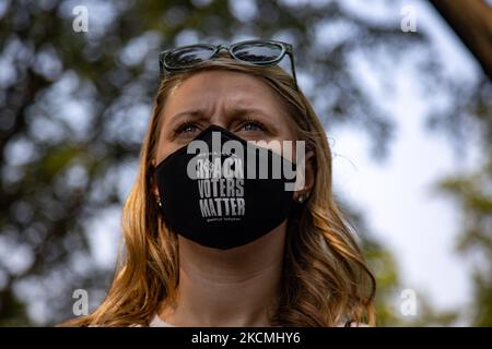 Eine Frau, die eine Maske der „Schwarzen Wähler“ trägt, sieht zu, wie Mitglieder des Kongresses bei der Wahlrechtskundgebung „Finish the Job: For the People“ am 14. September 2021 am Robert A. Taft Memorial in der Nähe der US-Senatsbüros in Washington, D.C., sprechen (Foto: Bryan Olin Dozier/NurPhoto) Stockfoto