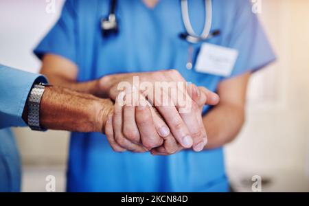 Ich bin bei jedem Schritt dabei. Ein nicht identifizierbarer junger Arzt hält seine älteren Patienten in der Hand, um sie zu unterstützen. Stockfoto