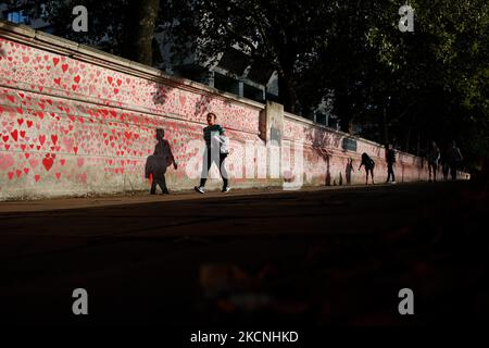 Am 27. September 2021 wandern die Menschen an der National Covid Memorial Wall am Südufer der Themse gegenüber dem Houses of Parliament in London, England. Die Mauer, die in diesem Frühjahr entstanden ist, besteht aus mehr als 150.000 bemalten Herzen, die jeweils ein Leben darstellen, das im Land für covid-19 verloren gegangen ist. (Foto von David Cliff/NurPhoto) Stockfoto