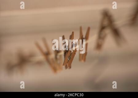 Eine Linie aus alten Holzklammern an einer Nylon-Wäscheleine mit rostigen Metallfedern bilden eine attraktive Anordnung vor einem dunklen und cremigen Hintergrund Stockfoto