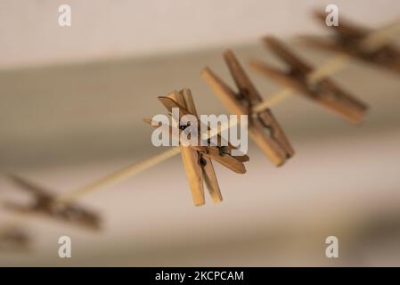 Eine Linie aus alten Holzklammern an einer Nylon-Wäscheleine mit rostigen Metallfedern bilden eine attraktive Anordnung vor einem dunklen und cremigen Hintergrund Stockfoto