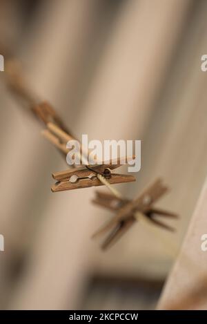 Eine Linie aus alten Holzklammern an einer Nylon-Wäscheleine mit rostigen Metallfedern bilden eine attraktive Anordnung vor einem dunklen und cremigen Hintergrund Stockfoto