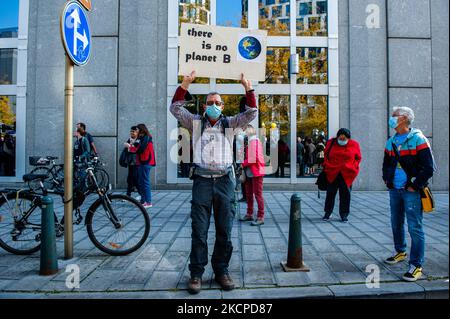 Ein Mann hält ein Klimaplakette in der Mitte auf der Straße, bevor die Demonstration Back to Climate am 10.. Oktober 2021 in Brüssel begann. (Foto von Romy Arroyo Fernandez/NurPhoto) Stockfoto