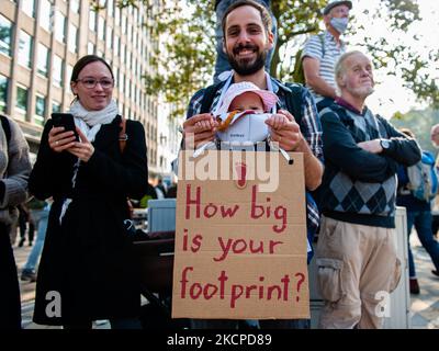 Ein Mann hält während der Demonstration Back to Climate, die am 10.. Oktober 2021 in Brüssel organisiert wurde, sein kleines Kind und ein Plakat zur Unterstützung des Planeten in der Hand. (Foto von Romy Arroyo Fernandez/NurPhoto) Stockfoto