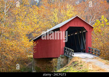 Rote traditionelle überdachte Brücke, umgeben von hellem Herbstlaub in der ländlichen Appalachia. Stockfoto