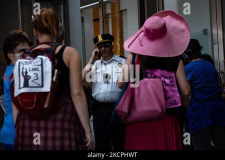 Ein Polizist nutzt sein Telefon, als sich Umweltaktivisten am 13. Oktober 2021 während der Jahrestagung der Association of the United States Army vor dem Mount Vernon Square Convention Center in Washington, D.C. versammeln. Die Aktion ist Teil einer Woche von Protesten, diese Proteste fordern Budgetkürzungen an das Finanzjahr, um den Verbrauch fossiler Brennstoffe zu reduzieren. (Foto von Bryan Olin Dozier/NurPhoto) Stockfoto