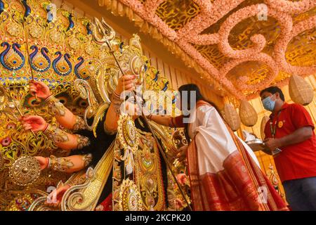 Eine Dame bietet dem Idol der Göttin Durga vor dem Eintauchen des Idols am letzten Tag des Durga Puja Festivals in Kalkutta, Indien, am 15. Oktober 2021 Süßigkeiten an. Sidur Khela oder Zinnoberspiel ist ein Ritual am letzten Tag der Durga Puja , Wo verheiratete Frauen der Gemeinschaft tupfen das Idol von Durga mit roter Farbe Zinnober oder Sindur und bietet Süßigkeiten an, bevor sie der Göttin am letzten Tag des Durga puja Festivals adjeu bieten. (Foto von Debarchan Chatterjee/NurPhoto) Stockfoto