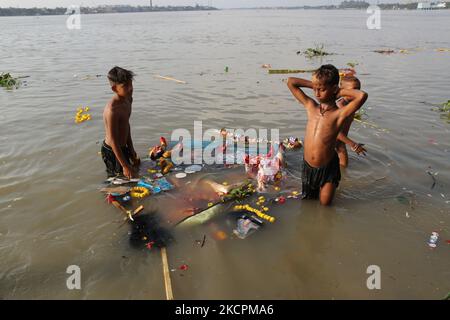 Ragpicker sammelt hinduistische Göttensstrukturen nach in den Ganges-Fluss von hinduistischen Anhängern während des Eintauchens von Durga-Idolen, in Kalkutta, Indien, 15. Oktober 2021. Am letzten Tag des Durga Puja-Festivals tauchen Hunderttausende von Idolen in Gewässer im ganzen Land ein, was ernsthafte Bedenken hinsichtlich der Umweltverschmutzung verursacht. (Foto von Debajyoti Chakraborty/NurPhoto) Stockfoto