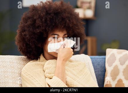 Krank, traurig und eine Frau mit Covid, die auf dem Sofa mit einer Decke in der Lounge eines Hauses die Nase bläst. Burnout, Virus und afrikanisches Mädchen mit einem Gewebe zum Abwischen Stockfoto