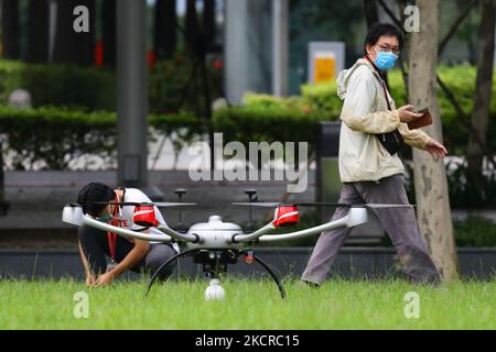 Zwei Männer mit Schutzmaske bereiten sich darauf vor, am 24. Oktober 2021 in Singapur eine Drohne in Marina Bay zu fliegen. (Foto von Suhaimi Abdullah/NurPhoto) Stockfoto