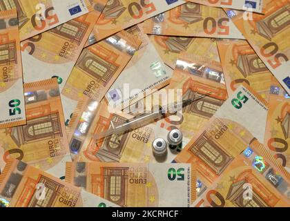 Ein illustratives Bild von fünfzig Euro-Banknoten, einer medizinischen Spritze und einer Impfstoffflasche. Am Montag, den 25. Oktober 2021, Kanada. (Foto von Artur Widak/NurPhoto) Stockfoto