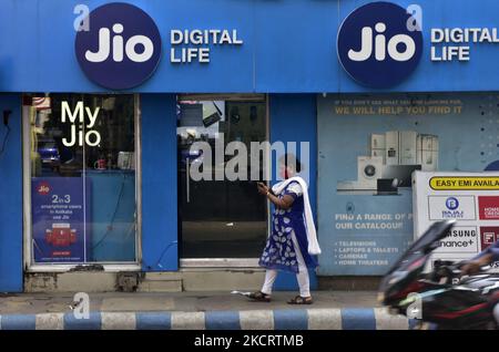 Eine Frau mit ihrem Mobiltelefon geht am 30. Oktober 2021 an einem Jio-Geschäft in Kalkutta, Indien, vorbei. Google und Jio Smartphone mit benutzerdefinierten android OS startet in Indien ab 04. November. (Foto von Indranil Aditya/NurPhoto) Stockfoto