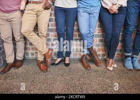 Die Füße fest auf dem Boden halten. Aufnahme einer Gruppe kreativer Kollegen aus dem unteren Winkel, die gemeinsam im Büro stehen. Stockfoto