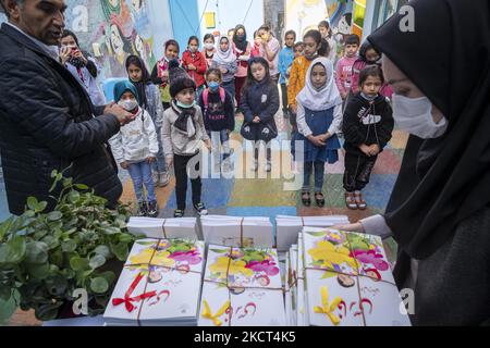 Afghanische Flüchtlingsschüler, die am ersten Tag des neuen akademischen Jahres auf den Empfang von Schulbüchern in der Farhang-Schule warten? Am 1. November 2021 in Südtehran. Die Farhang-Schule wurde 2000 vom afghanischen Flüchtling Nader Mousavi gegründet, der einen Master-Abschluss in Soziologie an der Universität von Teheran gemacht hat. Und jetzt, zwei Jahre nach dem Beginn des COVID-19-Ausbruchs im Iran, wo die Schule in Teilzeit betrieben wurde, hat sie ihren Vollzeitbetrieb aufgenommen und afghanische Schülerinnen und Schüler können die Schule besuchen. Familien müssen kein Geld dafür bezahlen Stockfoto