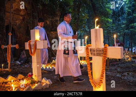 Ein Priester, der als Familie Gebete rezitiert, betet für seinen verstorbenen Verwandten, um den All Souls Day am 2. November 2021 auf einem Friedhof in Dhaka zu feiern. (Foto von Ahmed Salahuddin/NurPhoto) Stockfoto