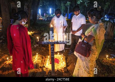 Ein Priester, der als Familie Gebete rezitiert, betet für seinen verstorbenen Verwandten, um den All Souls Day am 2. November 2021 auf einem Friedhof in Dhaka zu feiern. (Foto von Ahmed Salahuddin/NurPhoto) Stockfoto