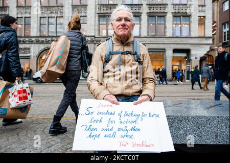 Während eines massiven Klimamarsches, der am 6.. November 2021 in Amsterdam organisiert wurde, sitzt ein Mann mit einem Plakat, auf dem ein Zitat von Greta Thunberg steht. (Foto von Romy Arroyo Fernandez/NurPhoto) Stockfoto