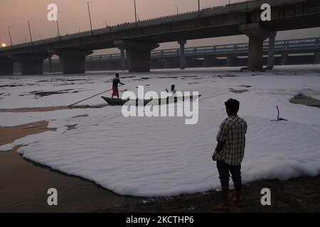 Ein Bootsmann rudert sein Boot in den verschmutzten Gewässern des Flusses Yamuna, bedeckt mit einer Schicht giftigen Schaums, während der Sonnenuntergang in Neu-Delhi, Indien, am 9. November 2021. (Foto von Mayank Makhija/NurPhoto) Stockfoto