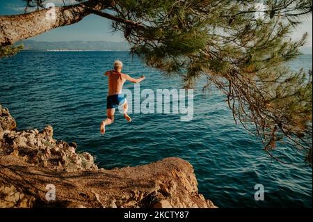 Sport im Sommerurlaub in Kroatien. Mann springt auf das Wasser und genießen Sie den Urlaub Stockfoto