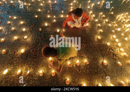 Eine Mutter und ein Sohn werden am 19. November 2021 Öllampen anlässlich der Dev Deepavali in Kalkutta, Indien, anzünden sehen. Dev Deepavali ist ein Hindu-Festival, das auf Karthik Purnima gefeiert wird, 15 Tage nach Diwali und wird angenommen, Diwali der Götter zu sein. Eifrige Anhänger leuchten Öllampe auf den Seiten des Ganges Flusses, um dem Fluss und seiner wohnenden Göttin Ehre zu erweisen. (Foto von Debarchan Chatterjee/NurPhoto) Stockfoto