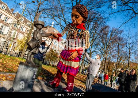 Die kleine Amal interagiert während ihres Besuchs in Den Haag mit einer der Skulpturen im Stadtzentrum, um am 19.. November 2021 in ganz Europa auf die Not junger Flüchtlinge aufmerksam zu machen, die aus Syrien geflohen sind. (Foto von Romy Arroyo Fernandez/NurPhoto) Stockfoto