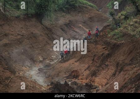 Die Bewohner reparierten Wasserleitungen, die von Erdrutschen getragen wurden, und schnitten den Zugang zur Hauptstraße von Darajat Pass Touristengebiet in Garut Regentschaft ab. Darajat Pass Garut ist ein Touristengebiet mit heißen Quellen im Dorf Padawaas, Garut Regency. Der Erdrutsch am Freitag (19/11/2021) Nachmittag führte dazu, dass der Zugang zum touristischen Gebiet des Darajat-Pass-Kraters abgeschnitten und Dutzende Hektar landwirtschaftlicher Flächen beschädigt wurden. (Foto von Algi Febri Sugita/NurPhoto) Stockfoto