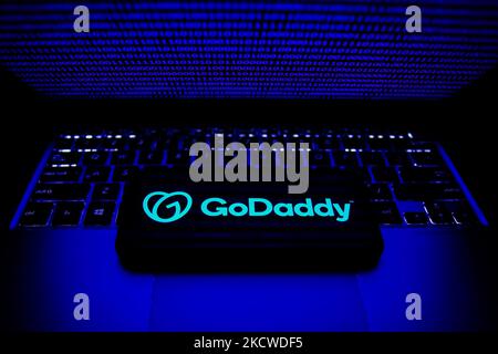 Das GoDrady-Logo auf einem Telefonbildschirm und der Binärcode auf einem Laptop-Bildschirm sind auf diesem Illustrationsfoto zu sehen, das am 22. November 2021 in Krakau, Polen, aufgenommen wurde. (Foto von Jakub Porzycki/NurPhoto) Stockfoto