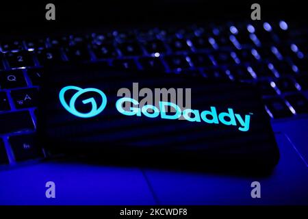 Auf einem Telefonbildschirm und einer Laptop-Tastatur ist das GoDardy-Logo zu sehen. Dieses Bild wurde am 22. November 2021 in Krakau, Polen, aufgenommen. (Foto von Jakub Porzycki/NurPhoto) Stockfoto