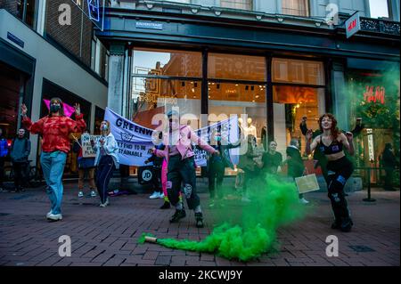 In Amsterdam führte eine Gruppe von Aktivisten des Extinction Rebellion einen Flashmob außerhalb des neuen H&M-Stores durch. Die Aktion richtete sich am 25.. November 2021 gegen die angeblichen Greenwashing-Praktiken der Modekette, um das Unternehmen grüner erscheinen zu lassen, als es tatsächlich ist. (Foto von Romy Arroyo Fernandez/NurPhoto) Stockfoto