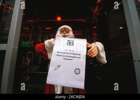Ein weihnachtsmann mit der Meldung „Eingang nur für geimpfte und wiedergeborene“ am Eingang eines Restaurants im Stadtzentrum von Düsseldorf, Deutschland, am 25. Nov 2021 (Foto: Ying Tang/NurPhoto) Stockfoto