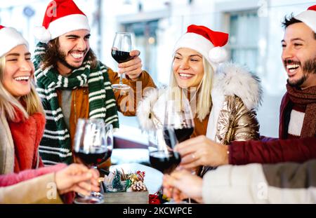 Millennial Freunde auf weihnachtsmütze Weihnachten mit Rotwein auf Food Street Market feiern - Winterurlaub Konzept für junge Leute, die Zeit und h genießen Stockfoto