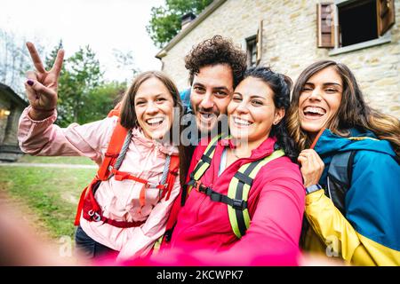 Happy Friends Gruppe macht Selfie bei Trekking-Ausflug mit Landhaus - Sportliches Lifestyle-Konzept mit jungen Millennials, die Spaß haben zu toge Stockfoto