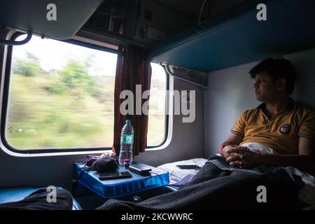 Juli 4. 2022 Haridwar Indien. Ein Mann in einem fahrenden Zug, der vor dem Fenster schaute und die Aussicht genoss. AC zweistufiger Trainer. Stockfoto