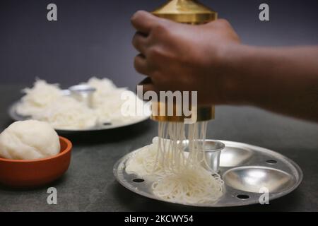 Frau, die Idiyappam am 28. November 2021 in Toronto, Ontario, Kanada, vorbereitet. Idiyappam (auch bekannt als String Trichter) ist ein Reisgericht aus den indischen Bundesstaaten Tamil Nadu und Kerala. Es besteht aus Reismehl, das zu Nudeln gepresst, in eine flache scheibenartige Form gewebt und gedämpft wird. (Foto von Creative Touch Imaging Ltd./NurPhoto) Stockfoto