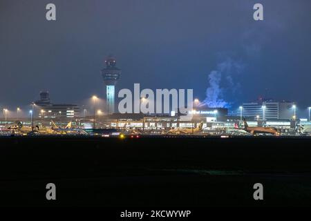 Nachtansicht des Flughafens Amsterdam Schiphol AMS mit Flugzeugen vor den Toren. 14 Fälle der neuen COVID-19-Variante Omicron wurden in den Niederlanden von Passagieren bestätigt, die aus Südafrika in die niederländische Stadt kamen. Mehr als 600 Passagiere wurden von den 2 Flügen getestet, wobei 61 positiv für Covid-19 bestätigt wurden. Die niederländische Polizei verhaftete zuvor zwei Passagiere, die sich in einem Quarantänehotel aufgehalten haben, als sie versuchten zu entkommen. Viele Länder haben Flüge nach Südafrika während einer bereits schwierigen Zeit mit der Coronavirus-Pandemie, die sich negativ auf die Luftfahrtindustrie auswirkte, eingestellt. Stockfoto